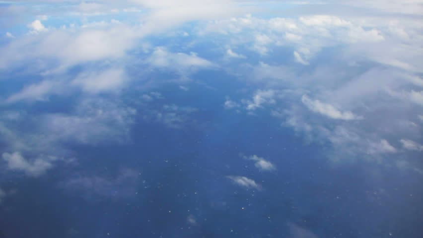 Flying in airplane over Pacific ocean dropping in altitude flying through clouds and little turbulence.