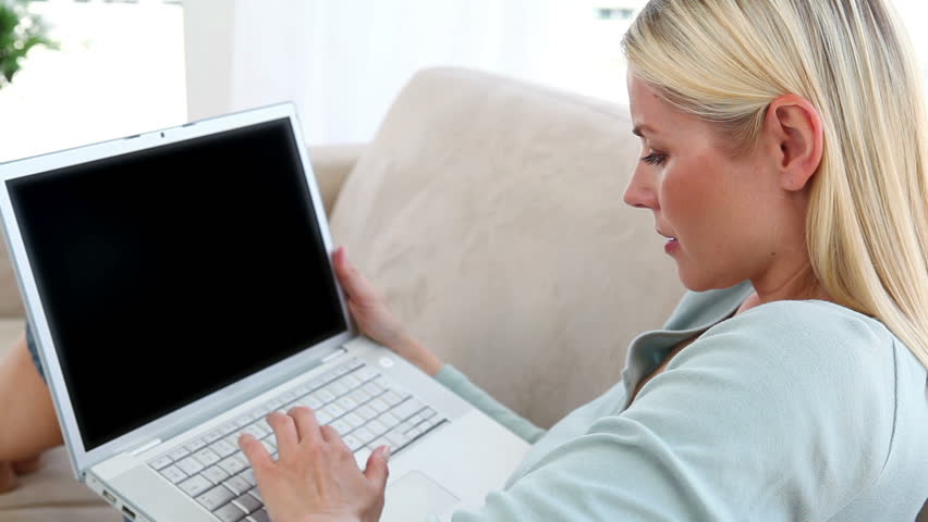 Blonde woman using a laptop on a sofa