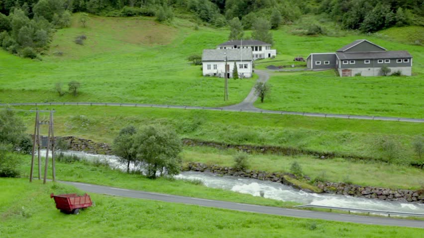 Several country houses near river among trees under moutain