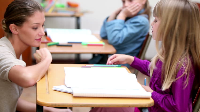 Teacher giving explanations to a pupil in the classroom