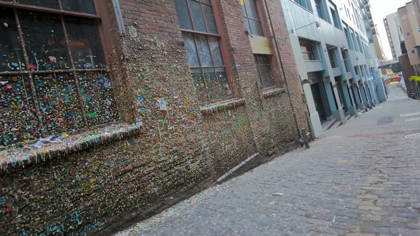 SEATTLE, USA - MAY 12, 2012: Timelapse of People walking by the gum wall on Post Alley in Seattle. the Market Theater Gum Wall is a brick alleyway wall now covered in used chewing gum.