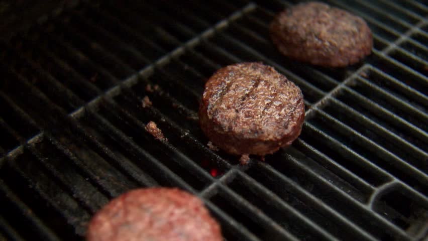 Flipping a burger over a bbq grill.