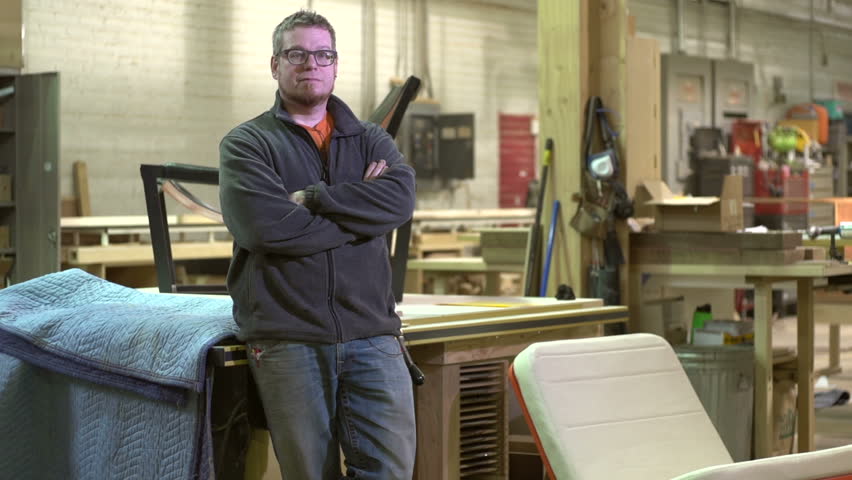 Proud owner of a woodworking business standing in his shop