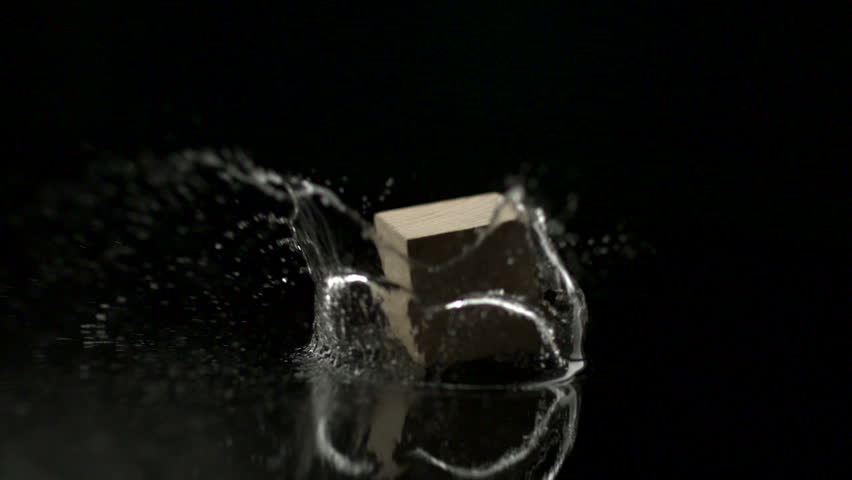 wooden block falling and spinning on water and making splash shooting with high speed camera.