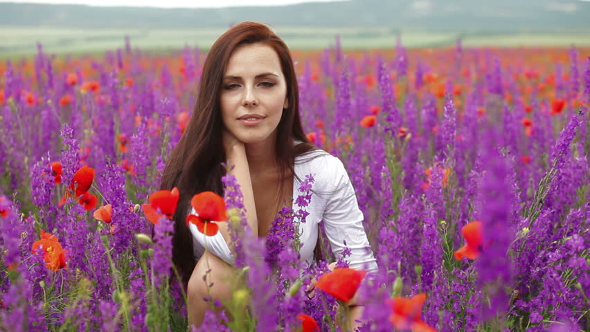 Attractive young woman posing in blossoming field