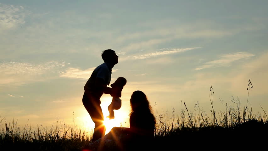 Happy family: father, mother and baby playing at sunset. Silhouettes