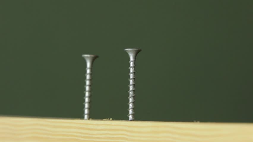 Carpenter using a screw gun to fasten some screws into a wood plank