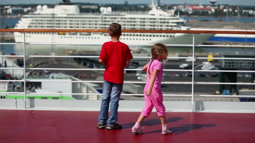 Children boy and girl throw pieces of bread to feed gulls in port at sunny day