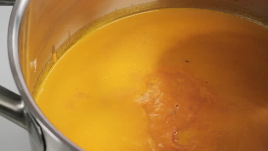 Stirring cream of tomato soup with a wooden spoon