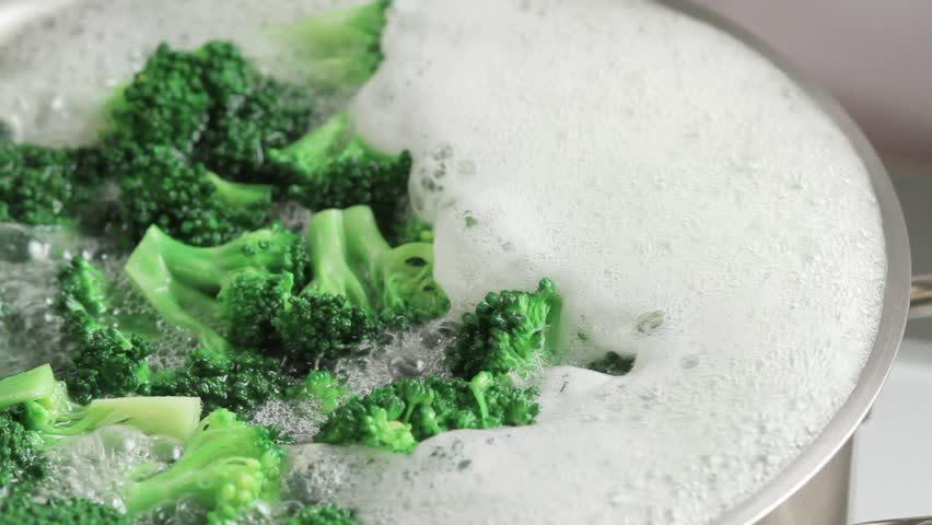 Removing broccoli florets from boiling water with a slotted spoon