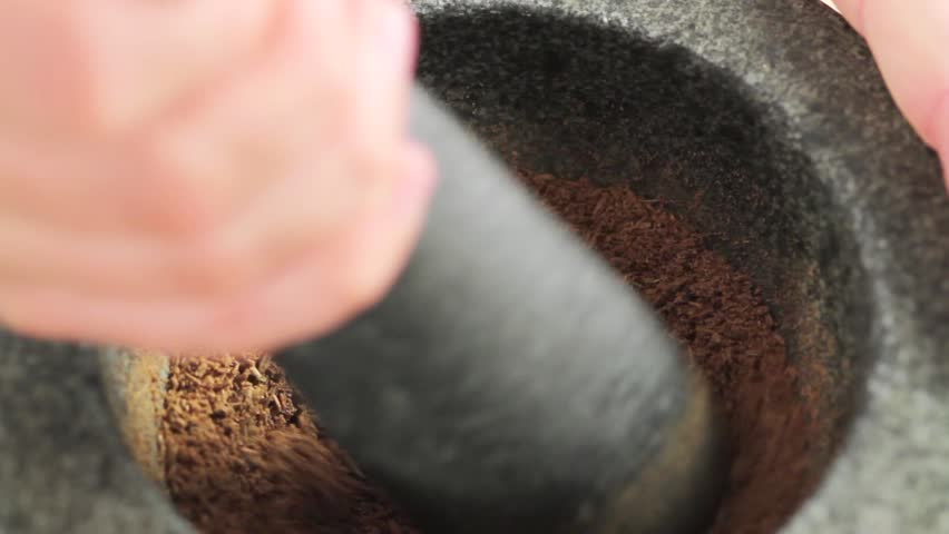 Crushing cumin in a mortar