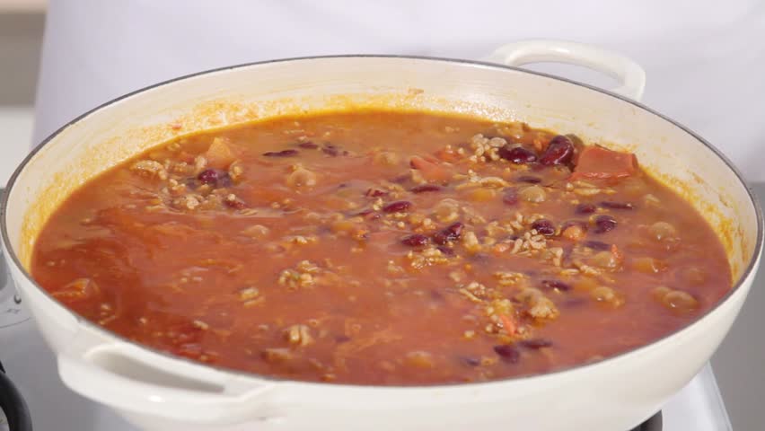 Adding oregano and seasoning to chilli con carne