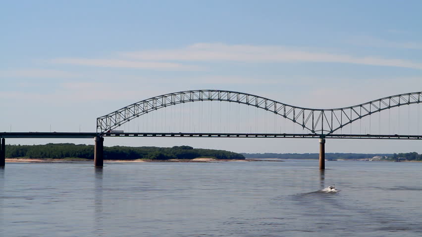 Traffic moves across the Mississippi River on Interstate 40 connecting Memphis, Tennessee and West Memphis, Arkansas as a small recreational powerboat speeds up the river.