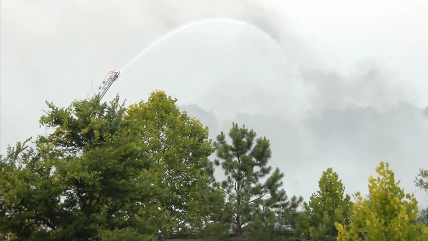 Smoke From Large Outdoor  Fire Being Sprayed By Ladder Mounted Remote Controlled Water Cannon