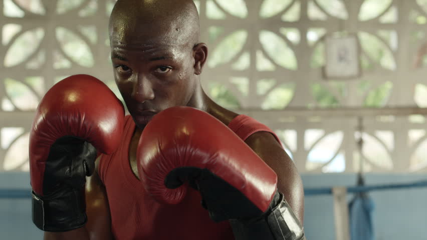 Portrait of strong black athlete on boxing ring looking at camera