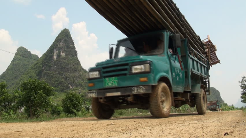 YANGSHUO - AUGUST 10 2010: A truck with bamboo rafts drives on a rural road in the tourist town of Yangshuo, China