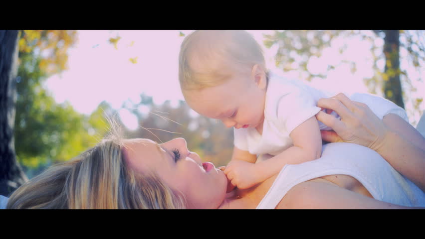 Blonde young mother and baby laughing together while playing outdoors shot in 5K widescreen RED EPIC