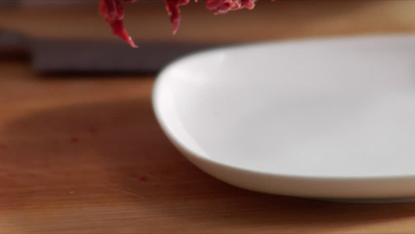 Close-up, slow pan over slices a Flat Iron steak and chef placing the slices on a plate.