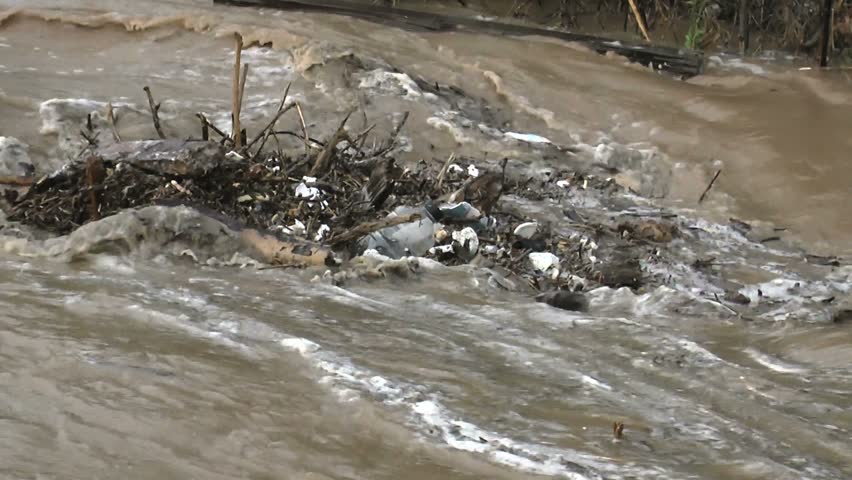 Close up, Trash pollutes water, swirls in eddy after heavy summer rains. 1080p