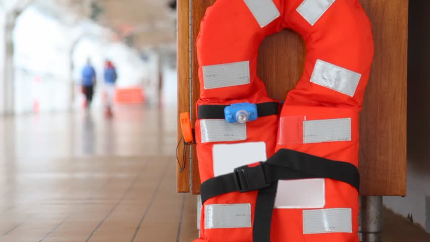 red life jacket on ship deck close up against walking people