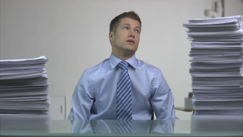 A tired man between piles of paper
