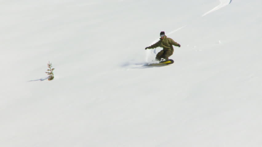 Male snowboarder carving through back-country powder