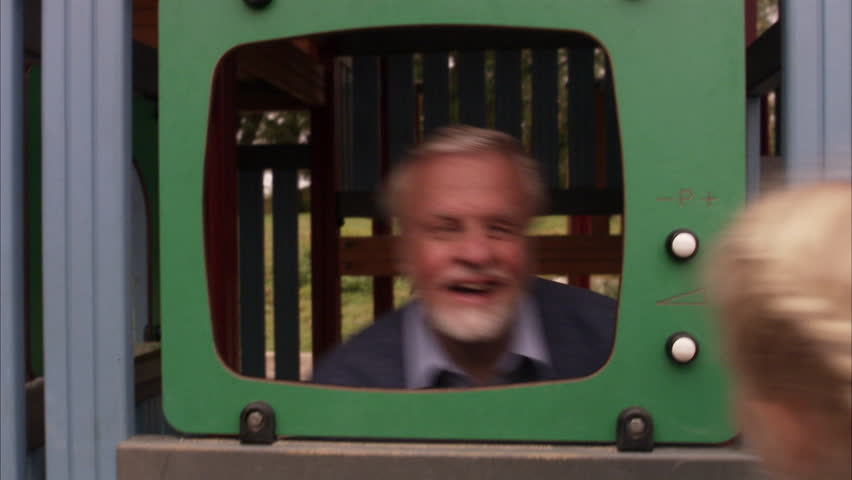 An elderly man with granddaughter in a playground