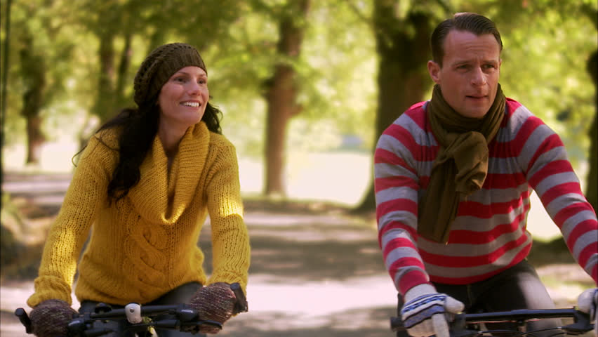 A woman and a man riding bicycles an autumn day