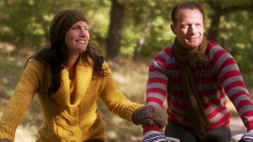 A woman and a man riding a bike an autumn day