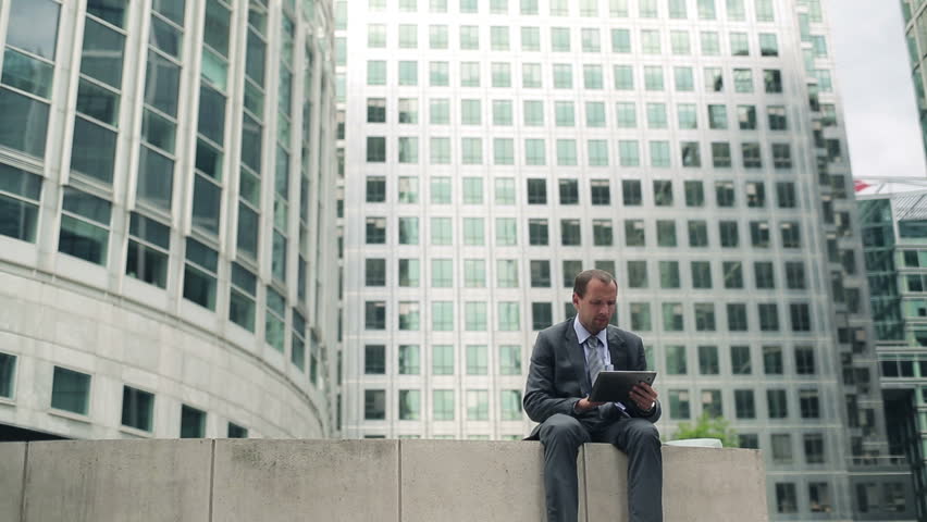 Businessman smoking cigarette and using tablet computer in the city
