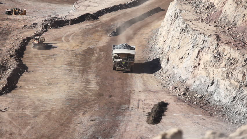Heavy equipment digs and hauls ore inside an enormus open pit mine. Chile (Two Shots)