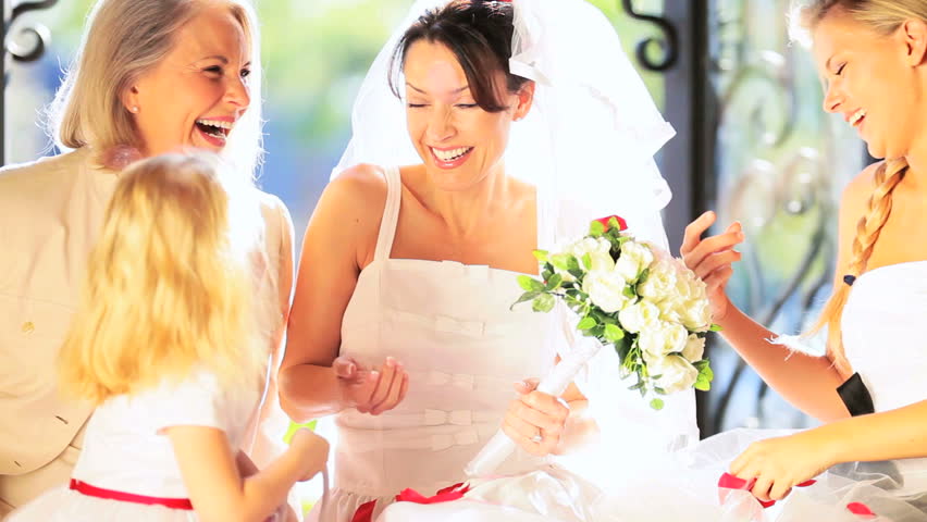 Little flower girl sitting with pretty bride mother and elegant grandmother on wedding day