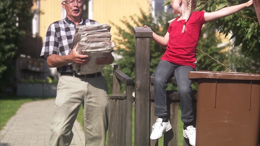 Girl and senior man recycling newspapers