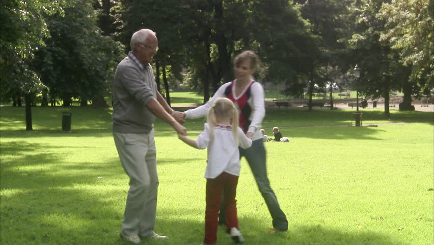 Senior man, woman and child dancing in a park
