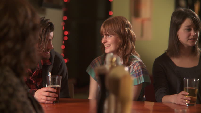 MS, PAN, Selective Focus, A woman ordering a beer at a bar and hanging out with her friends