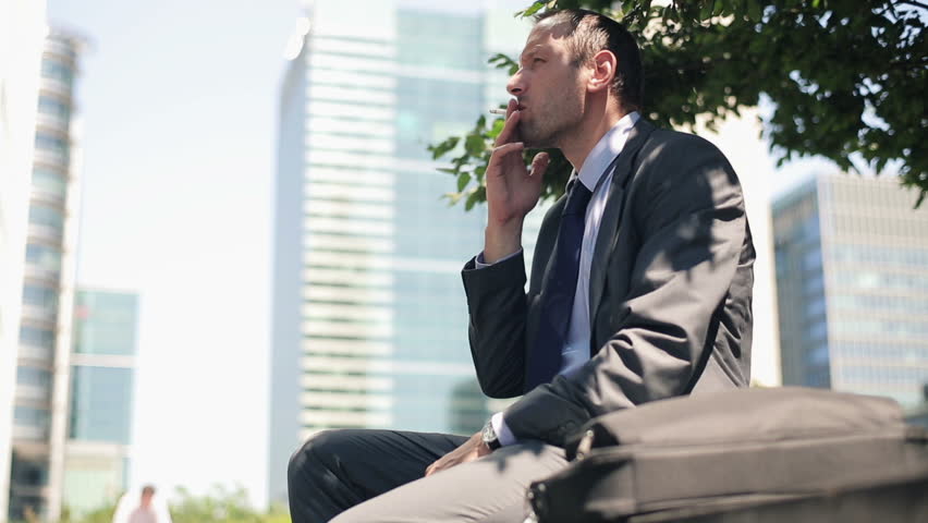 Businessman relaxing and smoking cigarette in the city

