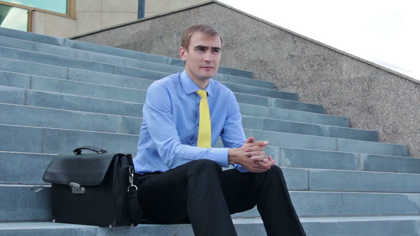 Young thoughtful businessman taking notepad and writing something