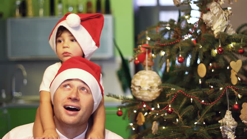 Portrait of father giving son piggyback ride near christmas tree
