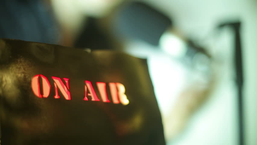 On air sign with a radio/tv announcer in the background