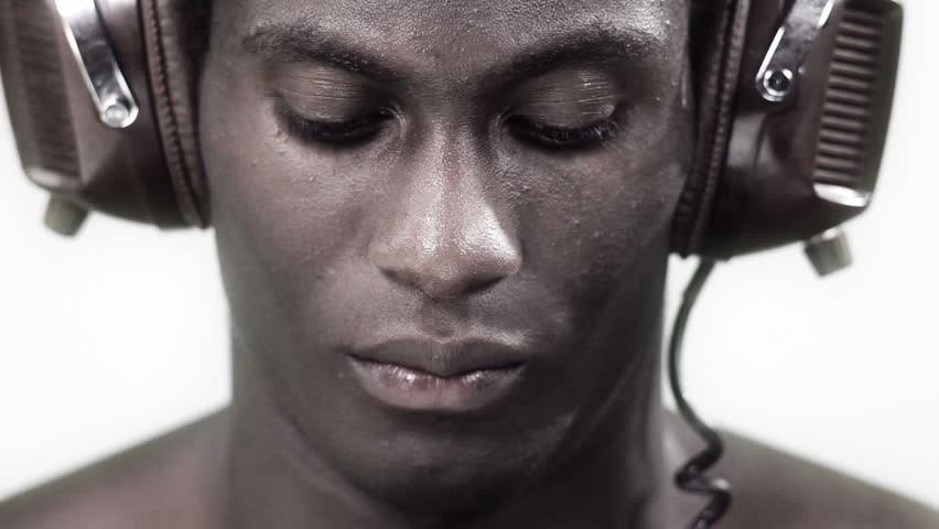 african young guy facing to the camera with a strong look with headphones in a silver style