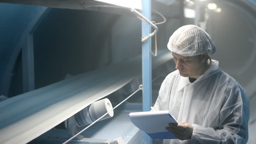 Worker controlling and writing the result of the quality of sugar on the production line
