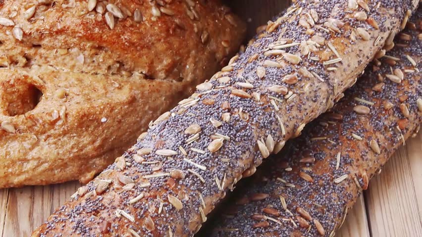 delicacy french rye breads and baguettes topped with sunflower and poppy seeds over wooden table