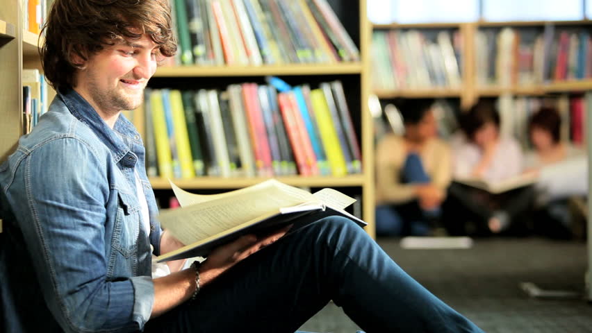 Young male Caucasian student studying university textbook in modern campus institution