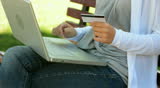 close up of woman holding credit card, typing on the keyboard and expressing gladness