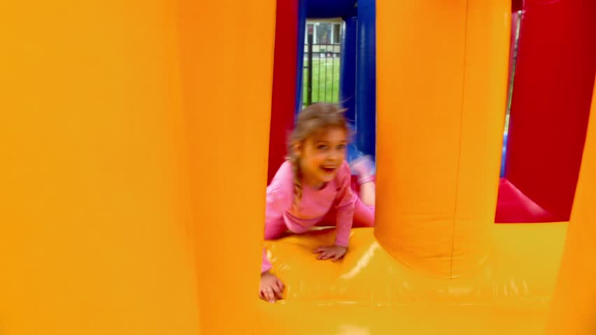 Two kids boy and little girl crawls at inflatable playground at sunny summer day