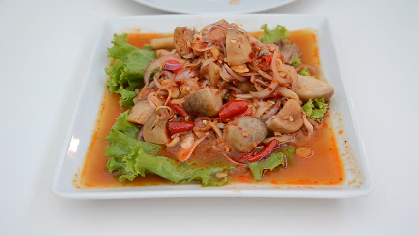 Spicy mingle mushroom salad gourmet. A person eating spicy Thai cuisine as main dish.