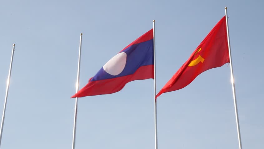 Laos and Communist flag waving against blue sky in Vientiane Laos