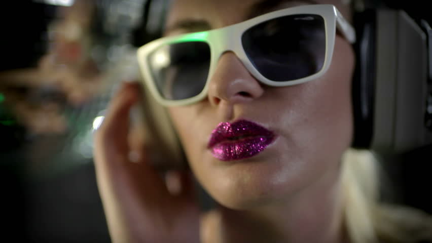 a sexy gogo dancer shot in a studio dancing and posing with a spinning disco ball. close crop on the face wearing cool sunglasses