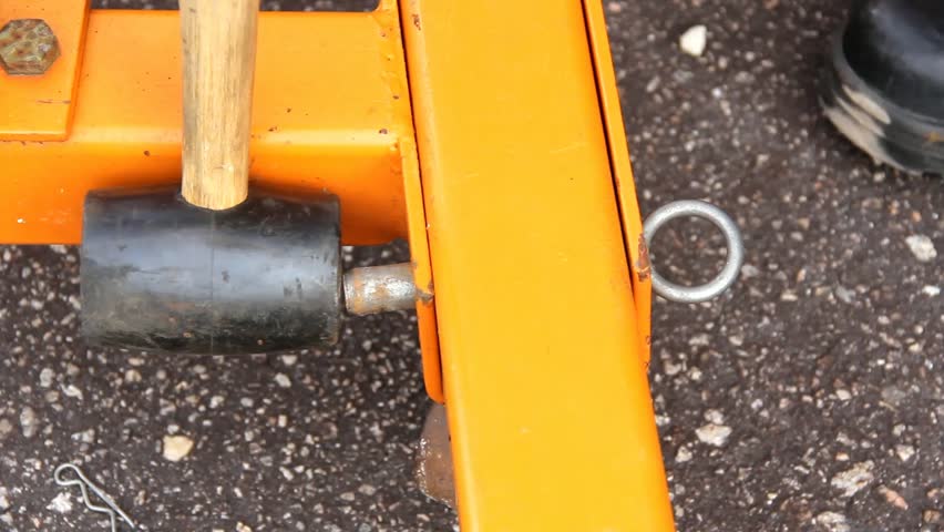 Rubber Mallet Taps Large Metal Pin Out And Back Just Above Pavement