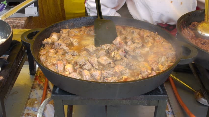 cooking hot meat stew in big metal pan